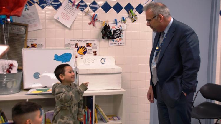 School District U46 CEO Tony Sanders speaks with a young boy at the first Language in the Laundromat site, which opened this spring at JetXpress Laundry on Dundee Avenue in Elgin. (School District U46)